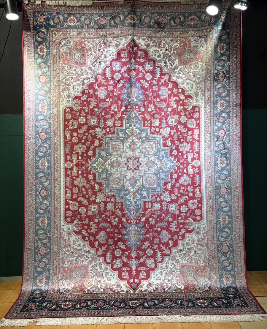 Machine-made carpet, crimson field with ivory star medallion and blue geometric border